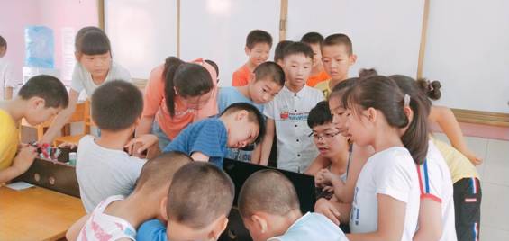 志愿者课间给孩子们放歌,孩子们围在志愿者旁边点歌
